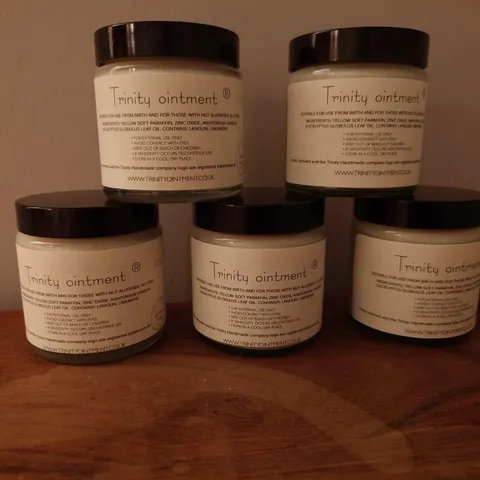 Trinity Ointment jar on a warm natural wood surface